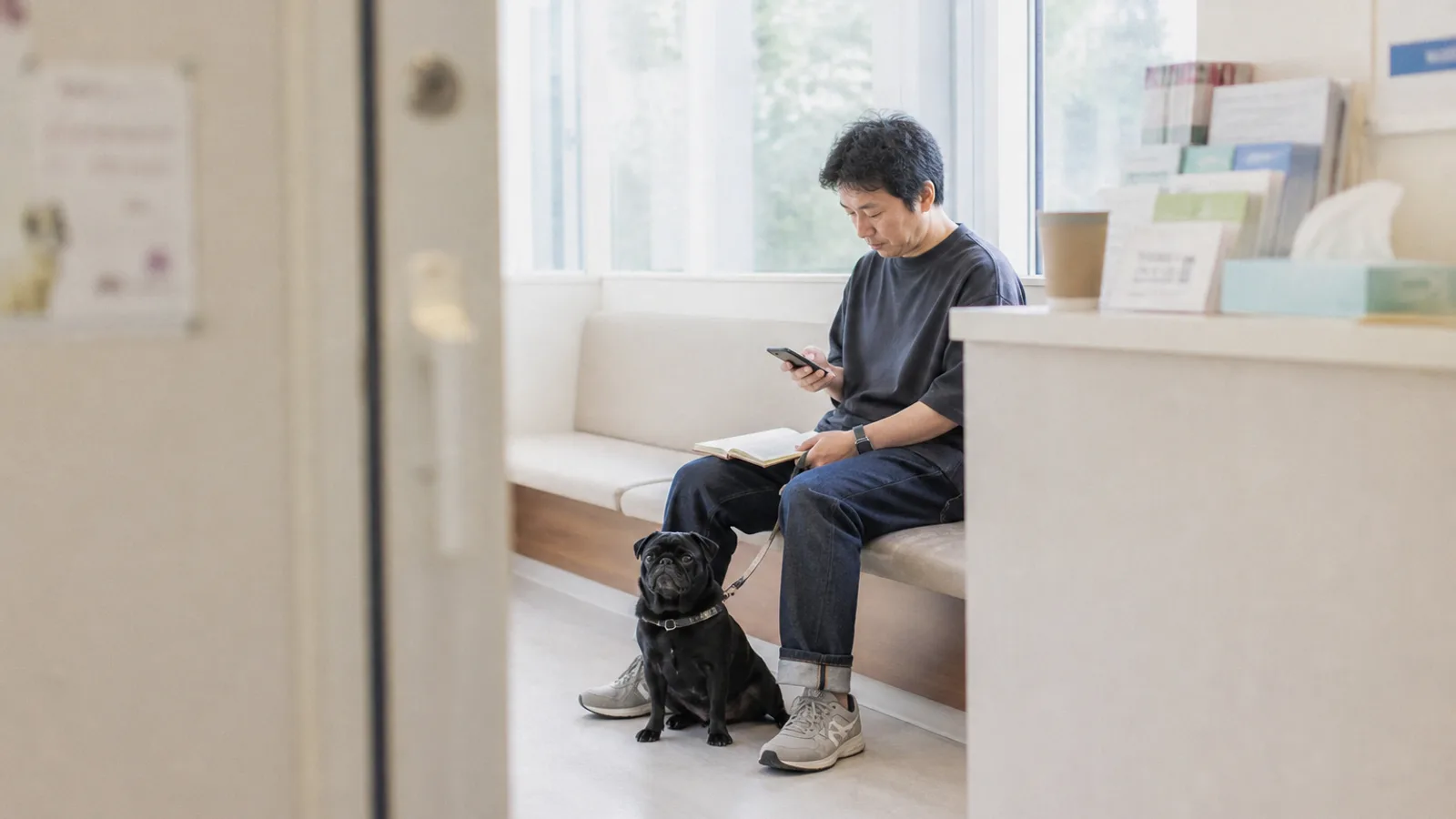 動物病院の待合室で記録を確認する飼い主。ワクチンや体重の記録があると、診察がスムーズになる