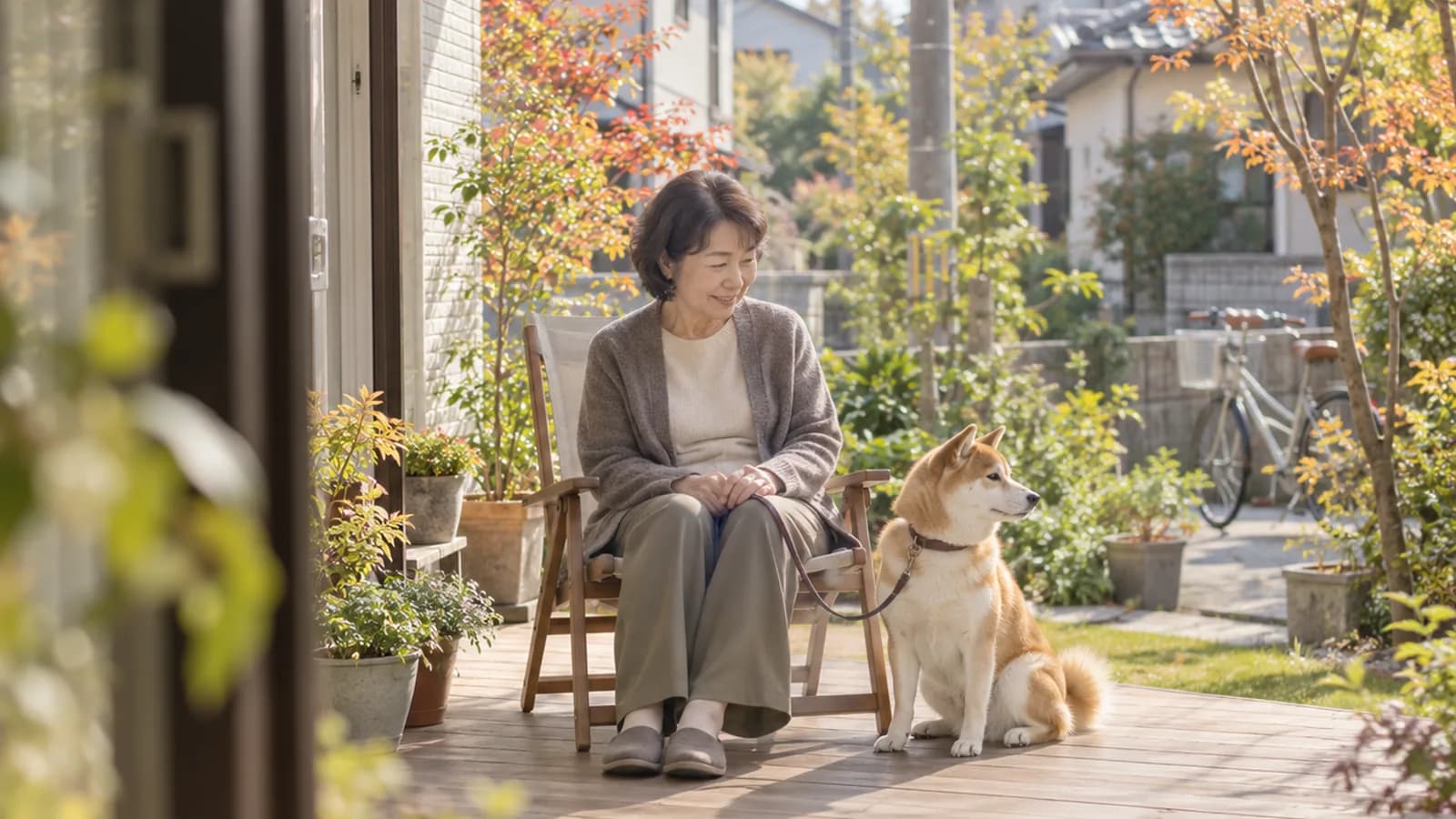ウッドデッキで、いすに座る飼い主の横に座る柴犬