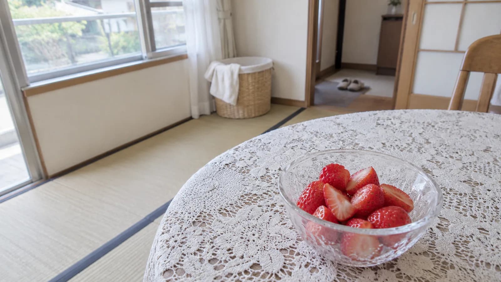 レースのクロスの丸テーブルに置いた、へたを取って切ったいちごの小鉢